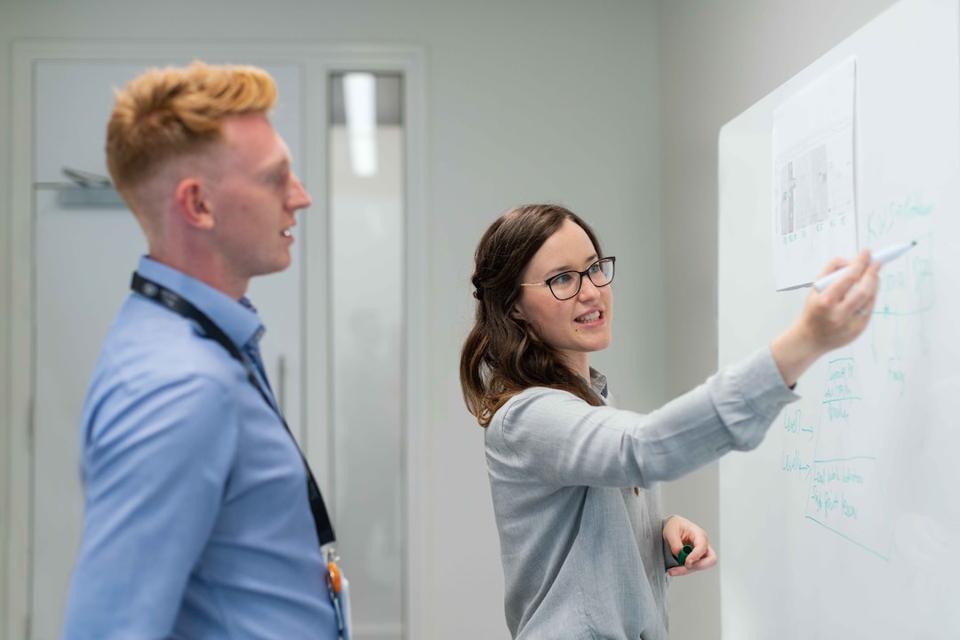 Two people standing at a whiteboard discussing implementing an account planning strategy